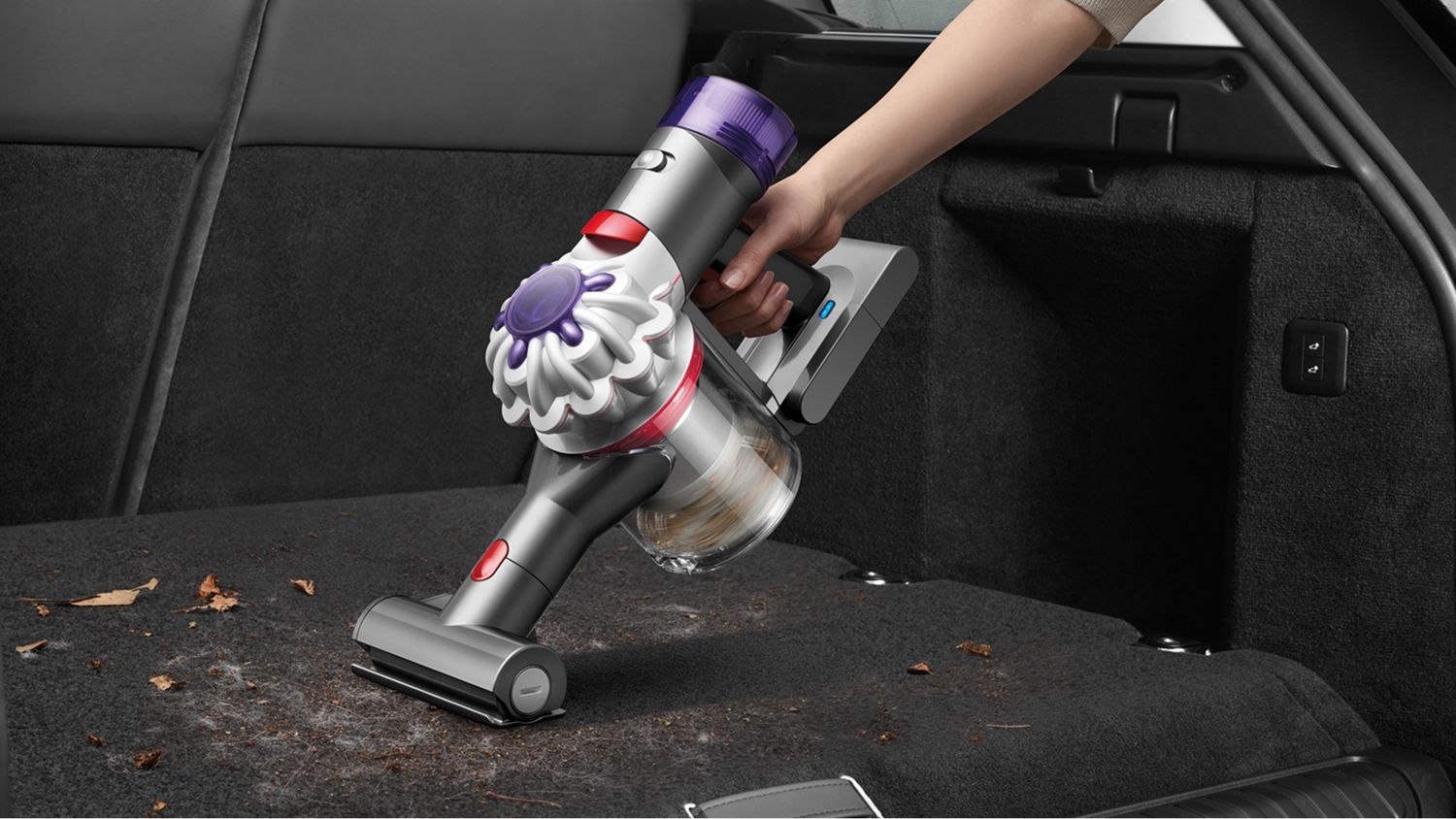 The Dyson Car+Boat handheld vacuum with the Mini motorised tool cleaning dirt inside of a car.